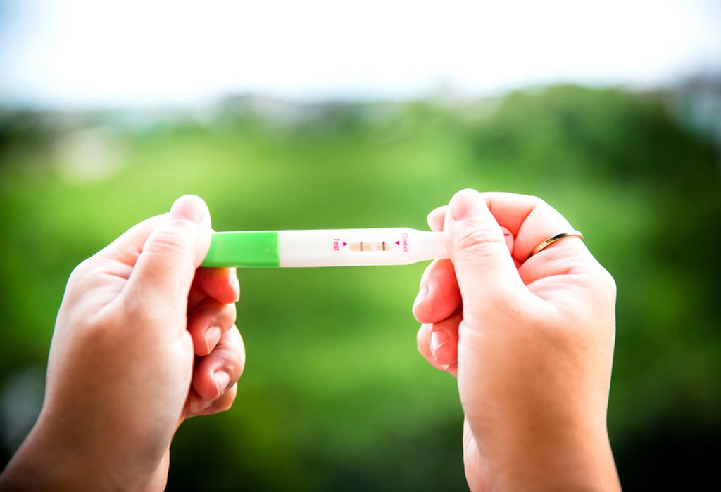 Une femme tenant un test de grossesse positif
