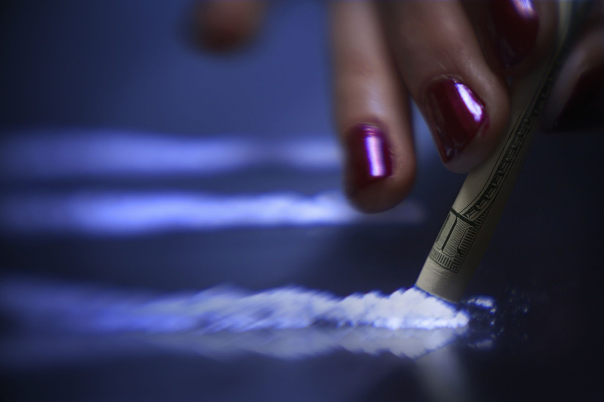 Femme reniflant de la cocaïne avec un billet de 100 $.