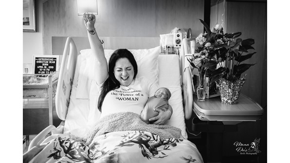 Femme tenant sa main dans la victoire dans la célébration tout en tenant le nouveau-né dans un autre
