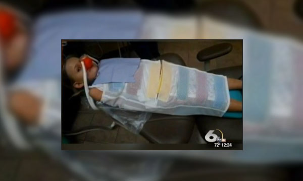 Enfant attaché sur une chaise de dentiste sans le consentement des parents