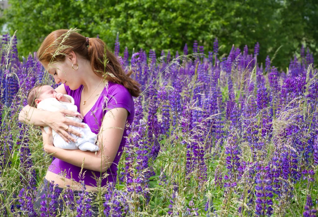 Conseils de soins aux nouveau-nés en été 3 Une mère tenant son bébé en se tenant debout dans un champ de lupin violet