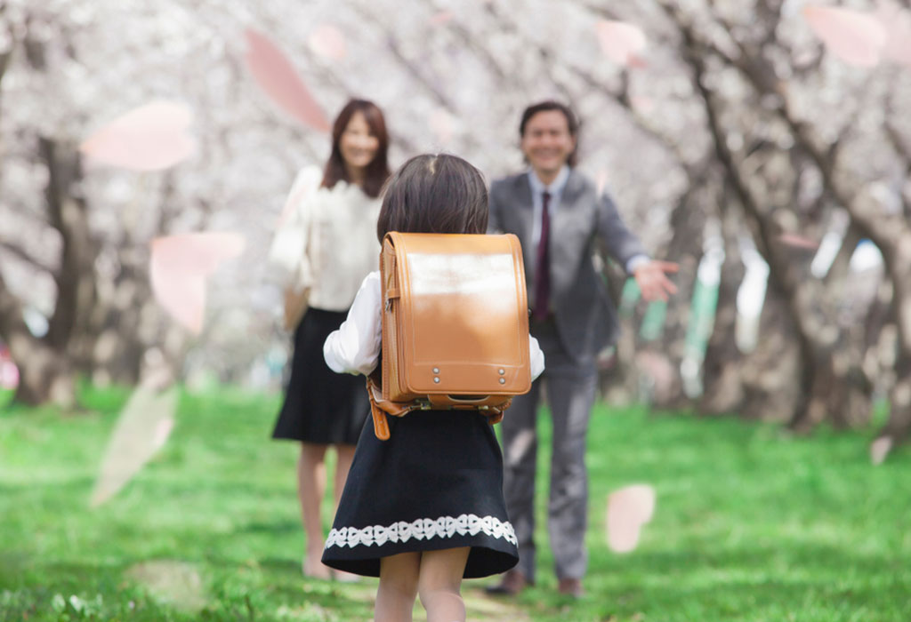 Ein kleines Mädchen geht mit ihren Eltern zur Schule