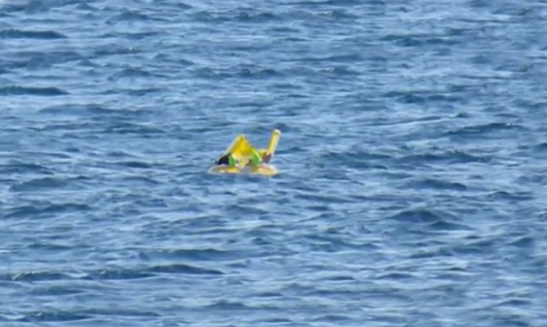Baby schwimmt auf See als Eltern, die sich sonnen